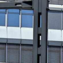 Dieser Bildausschnitt zeigt die Verbindung des Signalauslegers mit dem Grundmast. Der Signalausleger ist mittels einer geschraubten Flanschverbindung an den Winkelprofilen des Grundmastes befestigt. Die Flanschverbindung bietet eine plane Anlagefläche an die Winkelprofile, während die Knotenbleche zur Versteifung der Konstruktion dienen. Ebenfalls ist deutlich zu erkennen, wie die Winkelprofile mit den massiven Quadratrohrzuschnitten verschweißt sind. So werden die Lasten aus dem Ausleger gleichmäßig auf alle vier Profile verteilt und dem Mast so zusätzliche Stabilität verliehen.